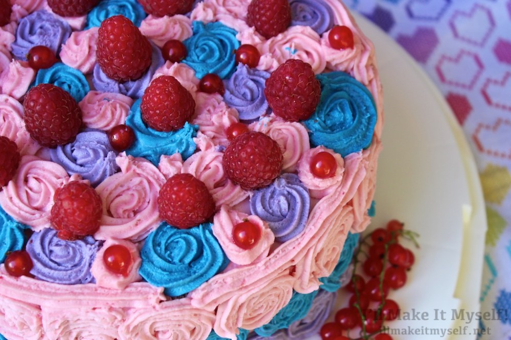 Image: bi pride birthday cake, with a pink-blue-purple ombre and frosting rosettes, decorated with raspberries and red currants