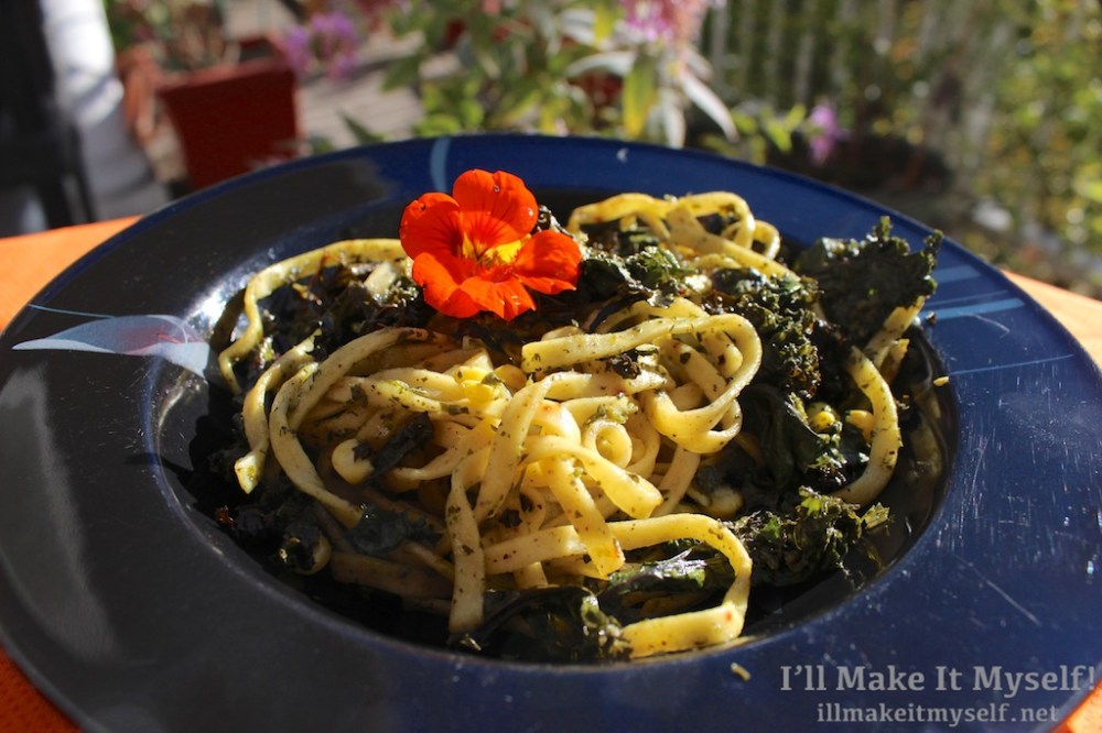 Image of pasta with pesto from recipe: egg noodles, roasted corn and kale, and a nasturtium on top.