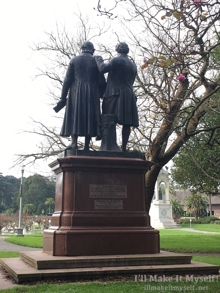 Image: The back of a statue of German authors and best friends Goethe and Schiller by Ernst Friedrich August Rietschel. Goethe is on the right in this photo in court dress and has his left hand on Schiller’s shoulder. Schiller is in a long coat.