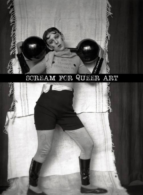 Image: black and white image of a light-skinned person with spit curls and 1920s-style Cupid's bow lipstick. They are holding fake barbells and wearing a shirt that says says "I am in training, don't kiss me."