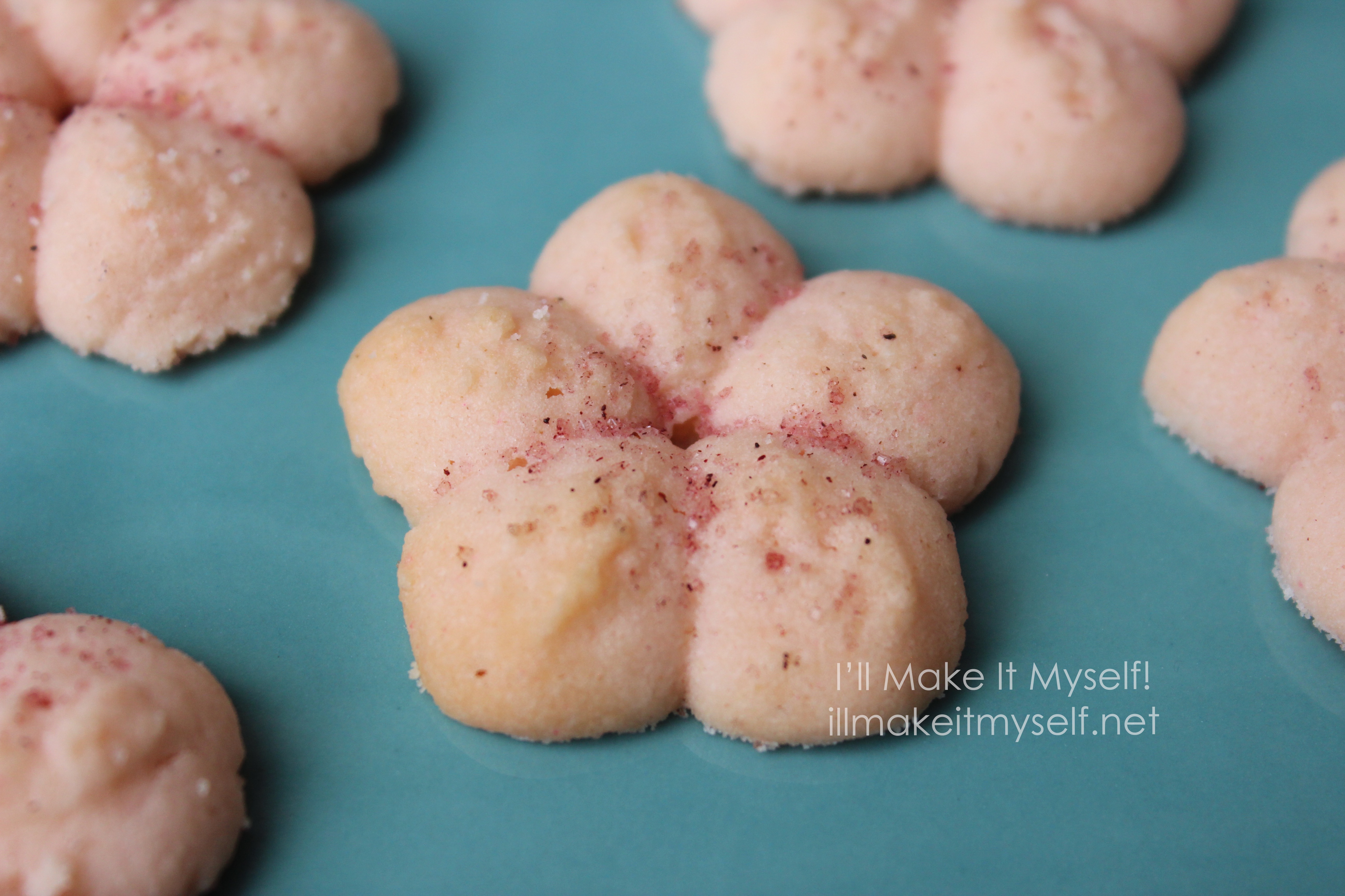 Close up of a cherry-blossom cookie on a teal plate