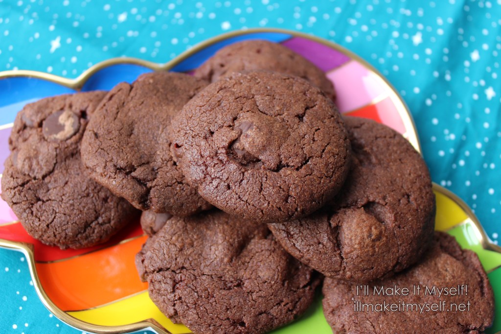 Close up of double-chocolate candy-cane cookies on a rainbow platter on a turquoise cloth with a star pattern.